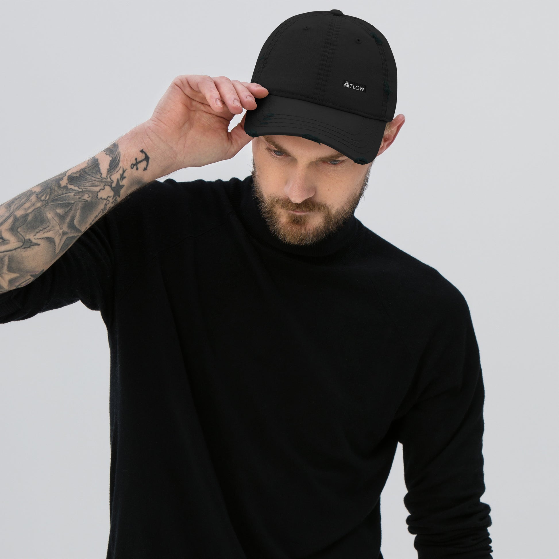 Man wearing a distressed dad hat in black, completing a stylish look with embroidered logo.